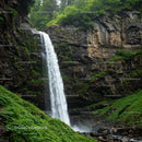 Cascading Waterfall Amidst Lush Greenery and Rocky Cliff