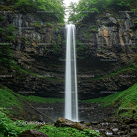 Majestic Waterfall Amidst Lush Greenery and Rocky Cliffs