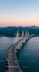 Suspension Bridge at Sunset Over Calm Waters and Mountains