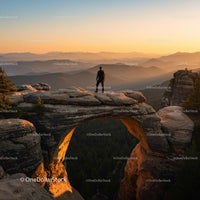 Lone Hiker on Majestic Stone Arch at Sunrise