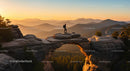 Hiker on Rocky Arch at Sunset in Majestic Mountains