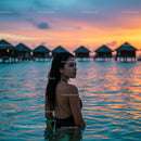 Woman in Tropical Lagoon at Sunset by Beach Huts