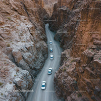 White Cars Navigating Through a Rocky Desert Canyon Road