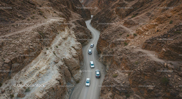 Vehicles on a Winding Road Through a Rocky Desert Canyon