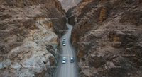 Convoy of Cars on a Winding Desert Canyon Road