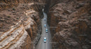 Aerial View of Cars Navigating a Rocky Desert Canyon