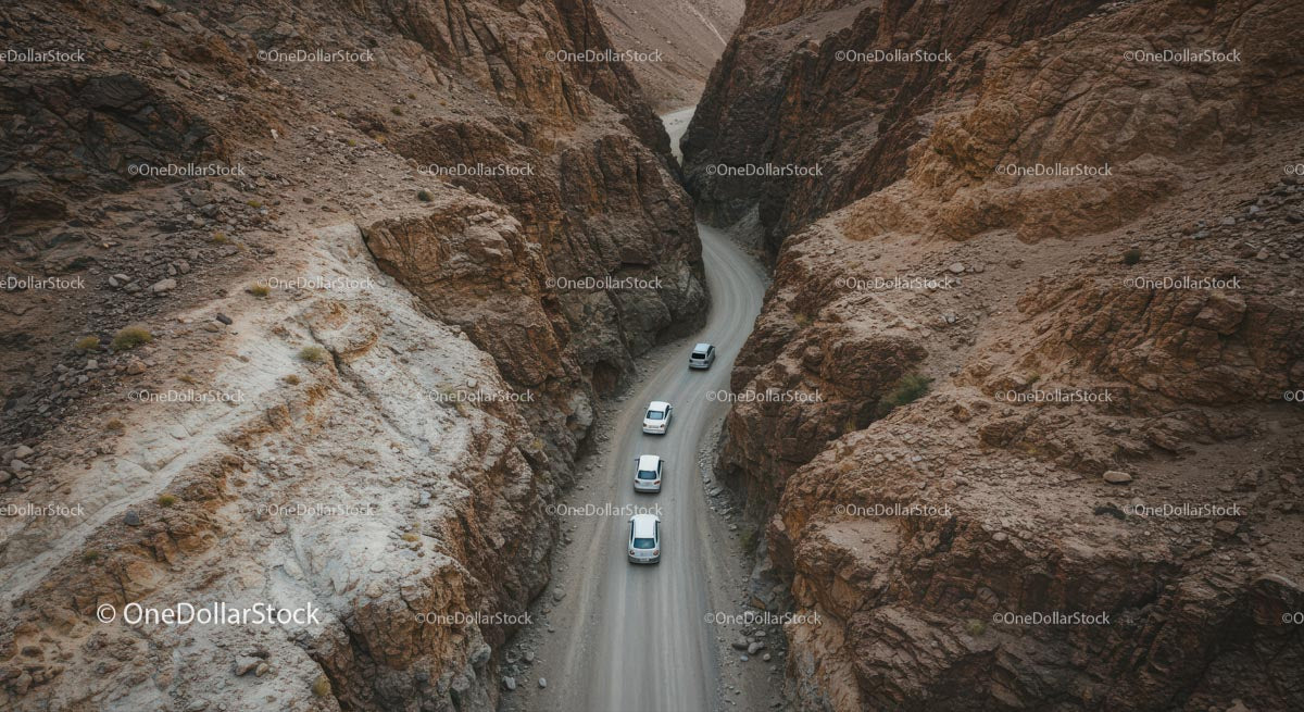 Convoy of Cars Navigating a Rocky Canyon Road