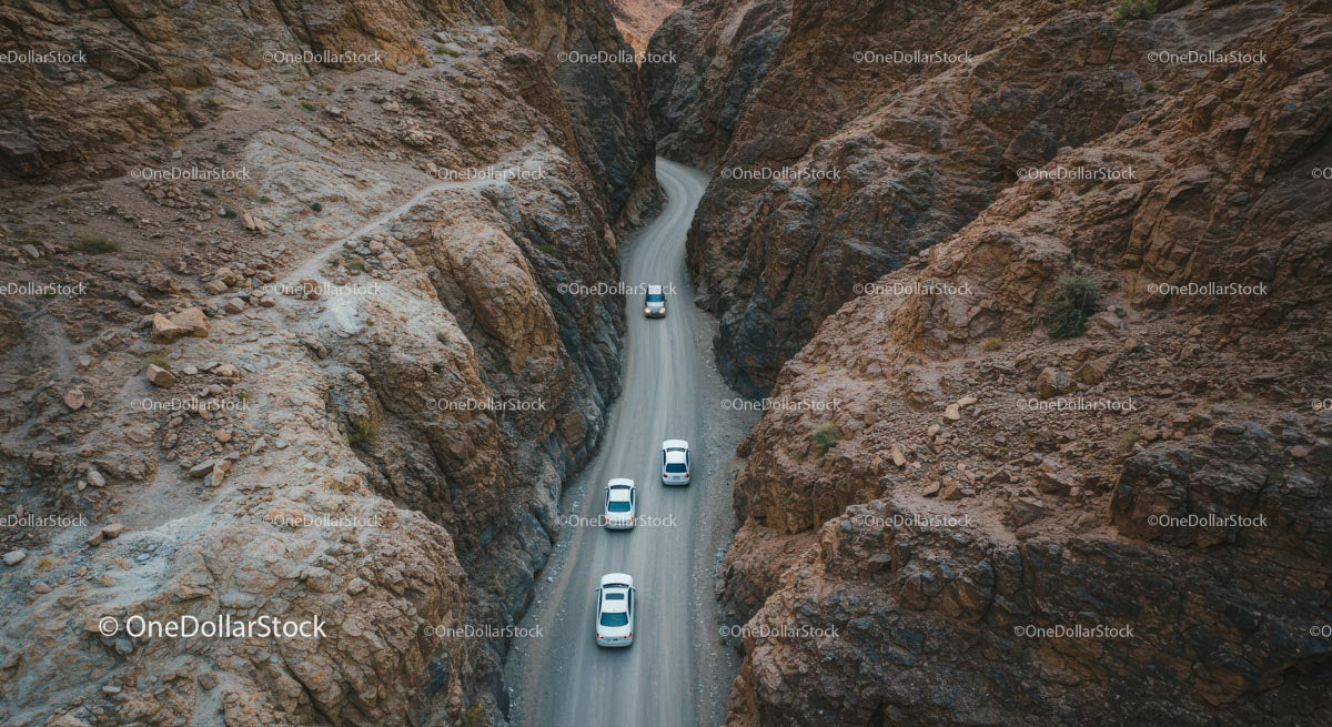 Cars Driving Through Narrow Canyon Road in Arid Landscape