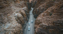 Cars Driving Through Narrow Canyon Road in Arid Landscape