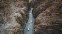 Cars Driving Through Narrow Canyon Road in Arid Landscape