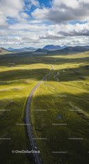 Winding Road Through Expansive Green Plains and Mountains