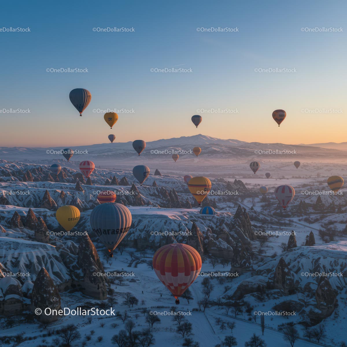 Balony na ogrzane powietrze nad ośnieżoną Kapadocją o wschodzie słońca