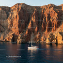 Yacht Sailing Along Dramatic Red Cliffs at Sunset