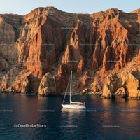 Yacht Sailing Along Dramatic Red Cliffs at Sunset
