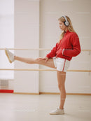 Young Woman Stretching in Red Jacket and Headphones
