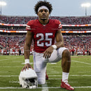 American Football Player Kneeling on Grass Field