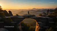Hiker on Natural Arch at Sunset with Mountain Views