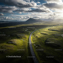 Aerial View of Winding Road Through Green Landscape and Mountains
