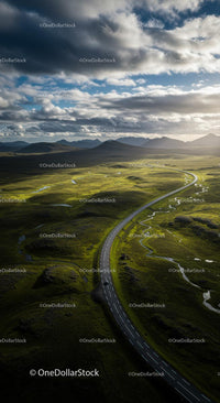Scenic Road Through Lush Green Highlands Under Dramatic Sky