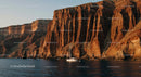 Sailing Boat Along Majestic Rocky Cliffs at Sunset