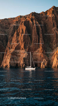 Sailing Yacht Against Majestic Rocky Cliffs at Sunset