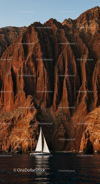 Sailing Yacht Beneath Majestic Red Rock Cliffs