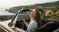 Joyful Woman Driving Convertible on Scenic Coastal Road