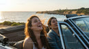 Two Friends Enjoy a Sunset Drive in a Convertible by the Ocean