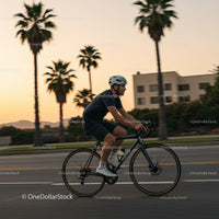 Cyclist Riding Past Palm Trees at Sunset