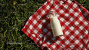 Milk Bottle on Red Checkered Picnic Blanket in Sunny Meadow