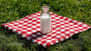 Milk Bottle on Red Checkered Picnic Blanket in Sunny Meadow