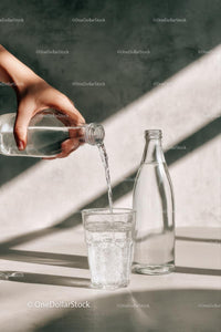 Pouring Water into a Glass with Sunlit Reflections