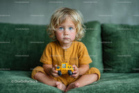 Blonde Toddler in Yellow with Toy Truck on Green Couch