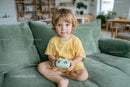 Adorable Toddler Sitting on Green Sofa with Toy