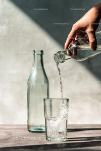 Pouring Water into a Glass with Sunlit Reflections
