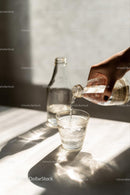 Pouring Water into a Glass with Sunlit Reflections