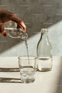 Pouring Water into a Glass with Sunlit Reflections