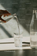 Pouring Water into a Glass with Sunlit Reflections
