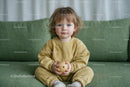 Adorable Toddler in Yellow Outfit on Green Sofa