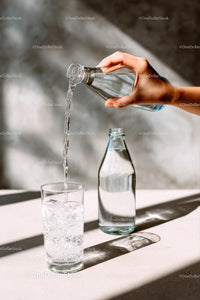 Pouring Water into a Glass with Sunlit Reflections