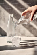 Pouring Water into a Glass with Sunlit Reflections