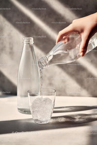Pouring Water into a Glass with Sunlit Reflections