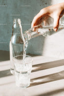 Pouring Water into a Glass with Sunlit Reflections