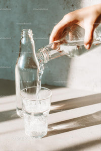 Pouring Water into a Glass with Sunlit Reflections