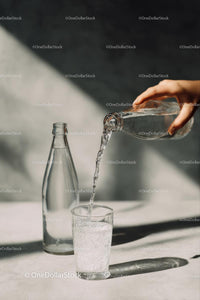 Pouring Water into a Glass with Sunlit Reflections