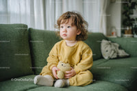 Cute Toddler Sitting on Green Sofa with Plush Toy