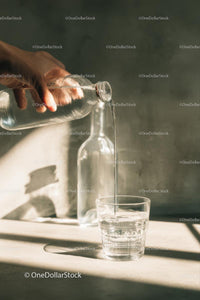 Pouring Water from Glass Bottle into Drinking Glass