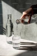 Pouring Water into Glass on Sunlit Surface