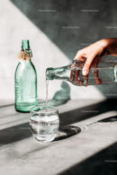 Pouring Water into a Glass with Sunlit Reflections