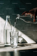 Pouring Water into Glass in Sunlit Kitchen